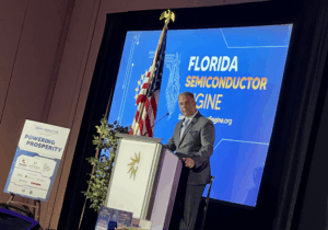 Ron Piccolo standing on stage at a podium addressing the conference.
