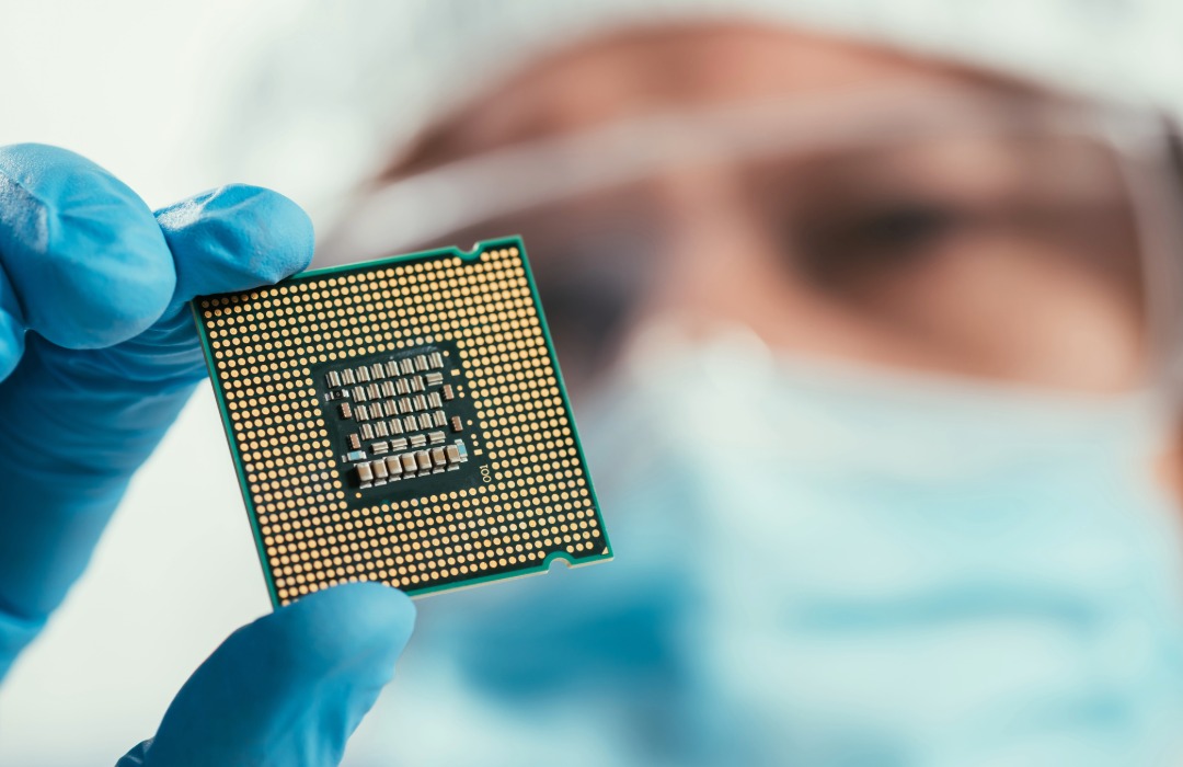 A worker in a semiconductor fab examines a chip display. Adobe stock photo.